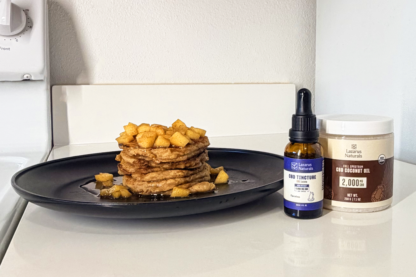 Lazarus Naturals Flavorless Tincture with Lazarus Naturals Coconut Oil next to finished recipe of apple cinnamon CBD pancakes